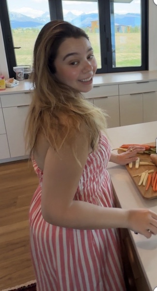 Ana in a red and white striped dress in a kitchen, turned towards the camera.